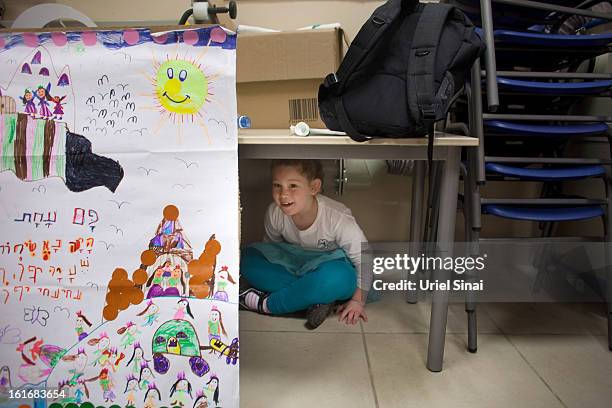 Girl hides under a table as Israeli schoolchildren take cover in a bomb shelter during a Home Front command drill simulating a rocket hitting a...