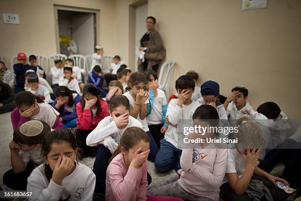 Israeli schoolchildren pray as they take cover in a bomb shelter during a Home Front command drill simulating a rocket hitting a school on February...