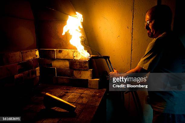 Worker uses a torch to make a piece of brass more malleable for shaping it into a trumpet bell in the manufacturing department of the E.K Blessing...