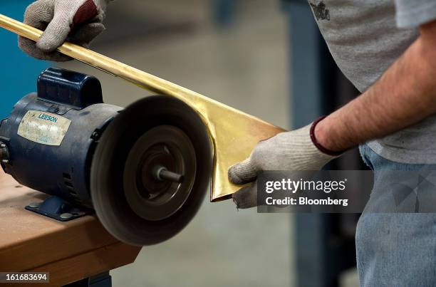 Worker uses a wire brush wheel to grind out a seam on a trumpet bell in the manufacturing department of the E.K Blessing Co. In Elkhart, Indiana,...