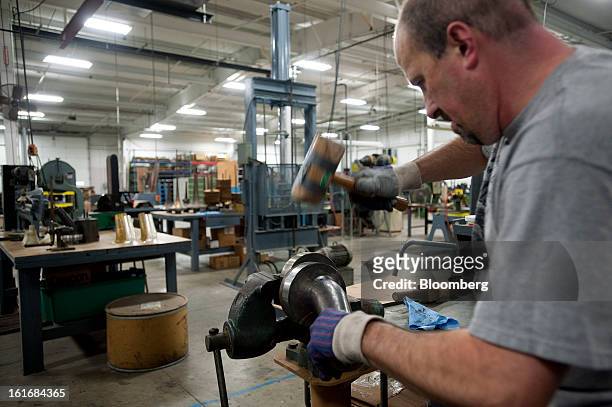 Worker uses a wooden hammer to shape a piece of brass on a metal mold into a trumpet bell in the manufacturing department of the E.K Blessing Co. In...