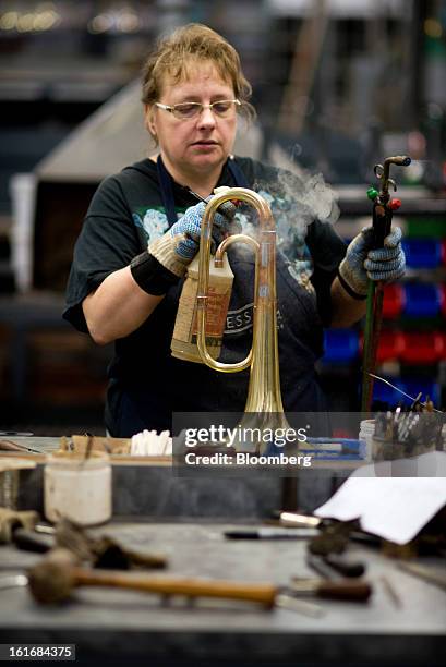 Worker sprays water on the hot tubes of a brass mellophone to cool it off during assembly in the manufacturing department of the E.K Blessing Co. In...