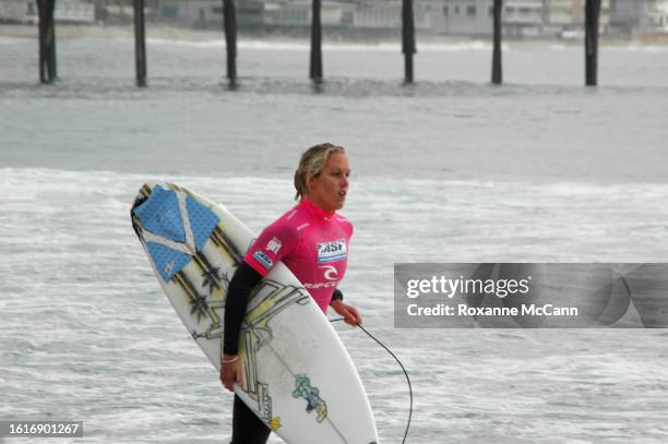 Australian surfer Chelsea Georgeson runs up the beach to compete in the 2005 Rip Curl Malibu Pro surfing contest wearing a black wetsuit with a hot...