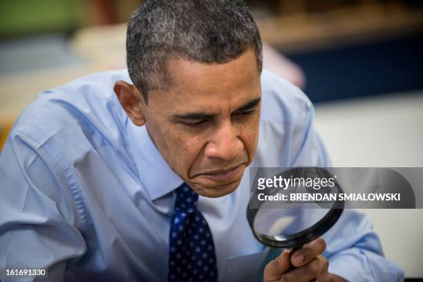 President Barack Obama uses a magnifying glass while he plays a learning game while visiting children at College Heights Early Childhood Learning...