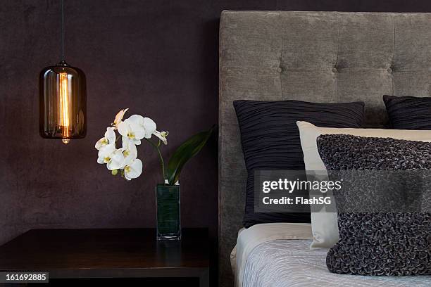 飾り枕で整えたベッドのヘッドボードのランプと蘭の花 - headboard ストックフォトと画像