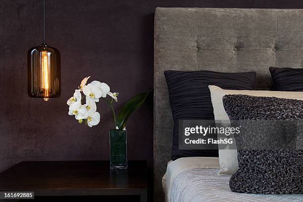 headboard detail with pillows lamp and orchid flowers - flower bed stockfoto's en -beelden