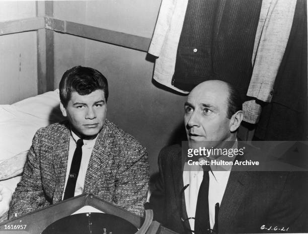 American singer Ritchie Valens sits with actor Milton Frome near a record player in a dressing room on the set of the film, 'Go, Johnny, Go!,'...