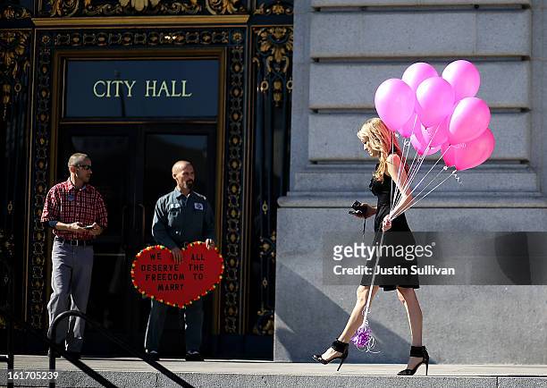 Same-sex couple Frank Capley and Joe Alfano look on as a woman carries Valentine's balloons in front of San Francisco City Hall on February 14, 2013...