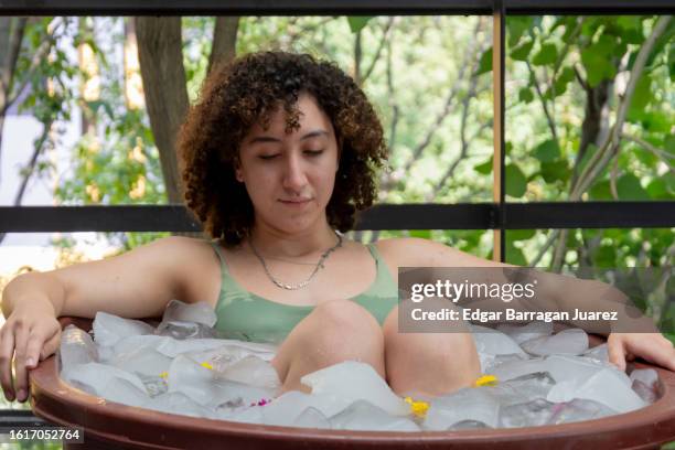 approach to a young woman who is taking an ice bath inside a tub - bad breath stockfoto's en -beelden