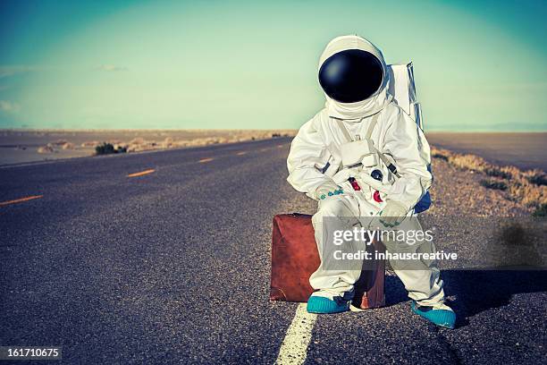 vintage astronaut sitting on luggage waiting for a ride - hitchhiking 個照片及圖片檔