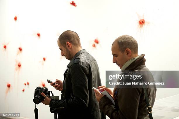 Two men look your phone front Los Carpintero's piece "Los Tomates" at Gallery Ivorypress from Spain during the "Feria Internacional de Arte...