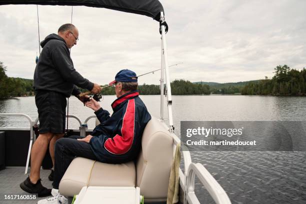 senior son and elderly father fishing on a lake. - men fishing stock pictures, royalty-free photos & images