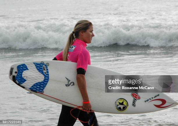 Peruvian surfer Sofia Mulanovich walks on Surfrider Beach at the 2005 Rip Curl Malibu Pro Surfing Contest wearing a black wetsuit and a hot pink...