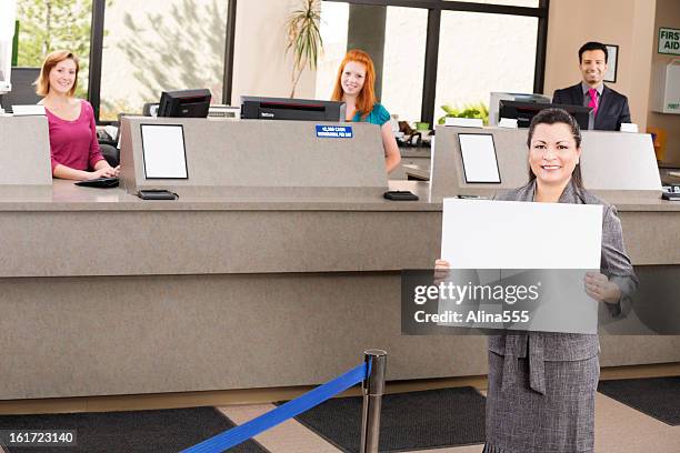 banker with blank sign and happy tellers at the bank - bank counter stock pictures, royalty-free photos & images