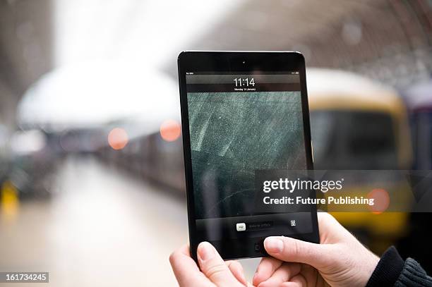 Close-up of a man using an Apple iPad Mini tablet computer at London's Paddington Station on January 14, 2013.