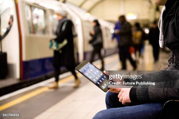 Man using an Apple iPad Mini tablet computer whilst waiting for an underground train on January 14, 2013.