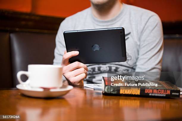 Man using an Apple iPad Mini tablet computer in a cafe setting on January 14, 2013.