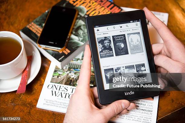 Close-up of a man using a Kindle Paperwhite e-reader in a cafe setting on January 14, 2013.