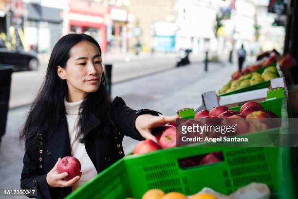 female buying produce exterior of market stall in cold - supermarket uk stock pictures, royalty-free photos & images