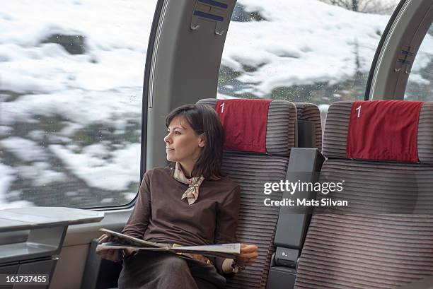 woman reading newspaper on a train - switzerland business stock pictures, royalty-free photos & images