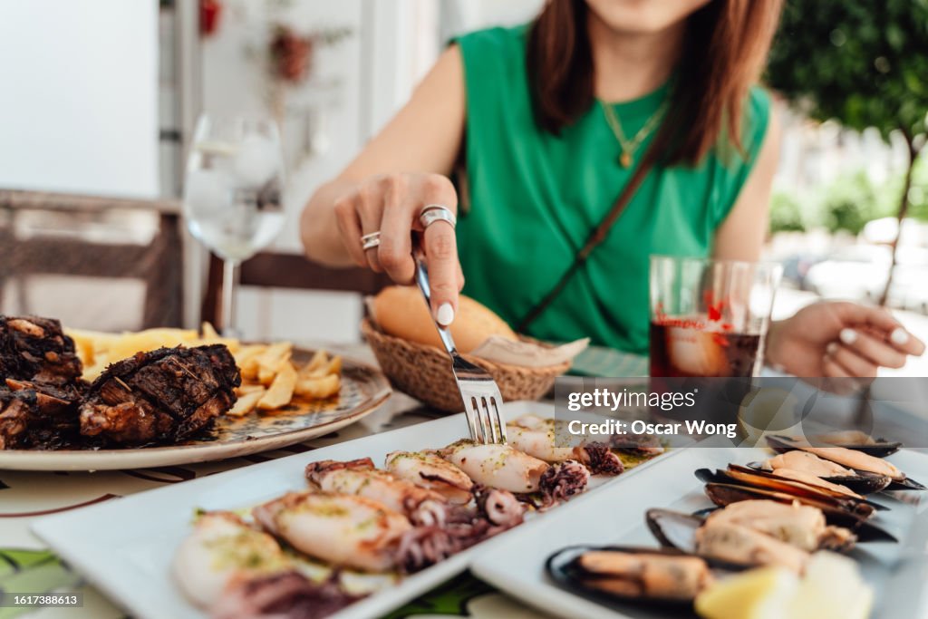 Mid-section of young Asian woman enjoying lunch at an outdoor Spanish restaurant