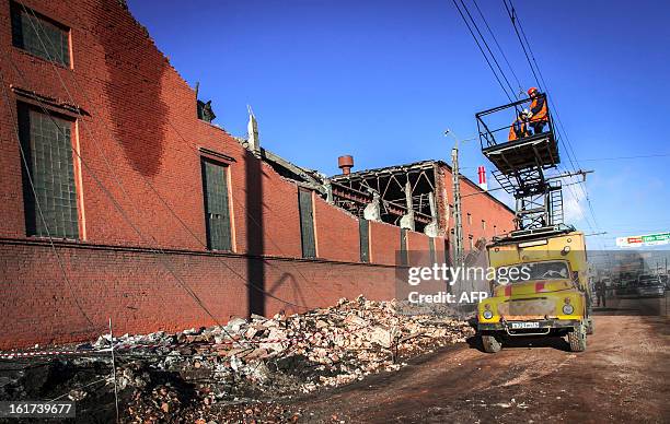 Workers repair a power line near the wall of a local zinc plant which was damaged by a shockwave from a meteor in the Urals city of Chelyabinsk, on...