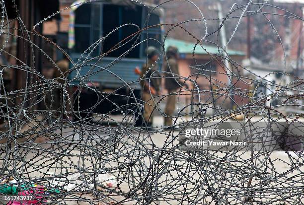 Indian paramilitary soldiers stand guard in front the concertina razor wire during a strict curfew on the seventh consecutive day, imposed after the...