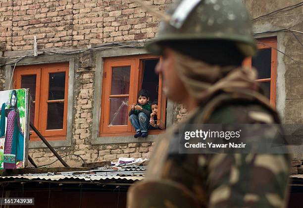 Kashmir Muslim Children look from the window of their house as an Indian paramilitary soldier stands guard during a strict curfew on the seventh...