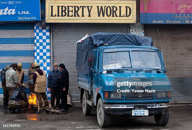 Indian policeman warm themselves on a bonfire as they guard the the streets during a strict curfew on the seventh consecutive day, imposed after the...