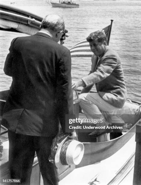 President John F Kennedy steps into the cockpit of the yacht, 'Marlin,' as Secretary of State Dean Rusk walks aft, Hyannis Port, Massachusetts, July...