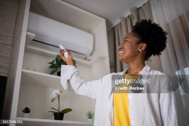joven enciende aire acondicionado - aire acondicionado fotografías e imágenes de stock