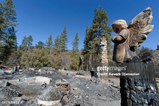 Statue of an angel stands on a wood column in front of the burned out cabin where remains of murder suspect former Los Angeles Police Department...