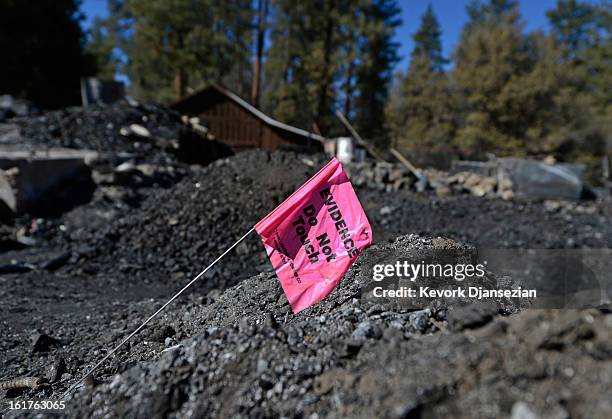 An evidence flag belonging to San Bernardino County Sheriff's crime scene investigators sits on pile of rubble inside the burned out cabin where the...