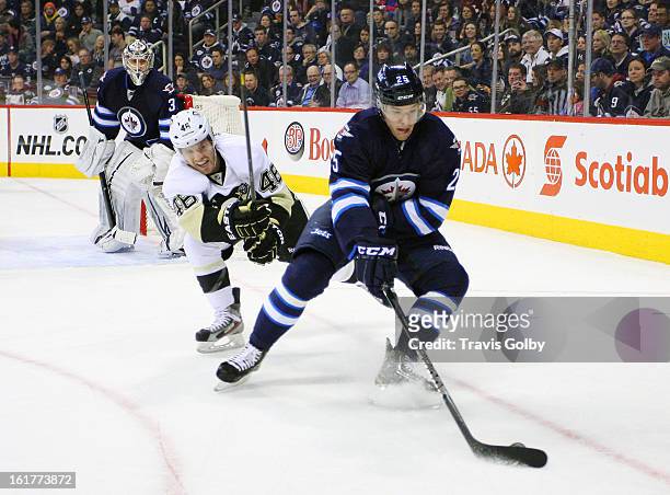 Zach Redmond of the Winnipeg Jets plays the puck away from Joe Vitale of the Pittsburgh Penguins as goaltender Ondrej Pavelec keeps an eye on the...