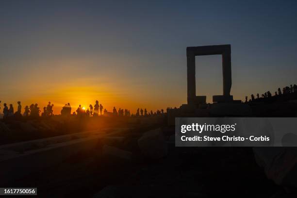 Pilgrimage of tourists at sunset to the Temple of Apollo or The Great Door is a massive marble doorway that stands proudly as the jewel of Naxos, on...