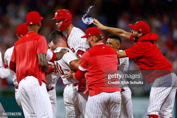 Trea Turner of the Philadelphia Phillies jumps into the arms of J.T. Realmuto as his teammates celebrate his two-run walk off single to defeat the...