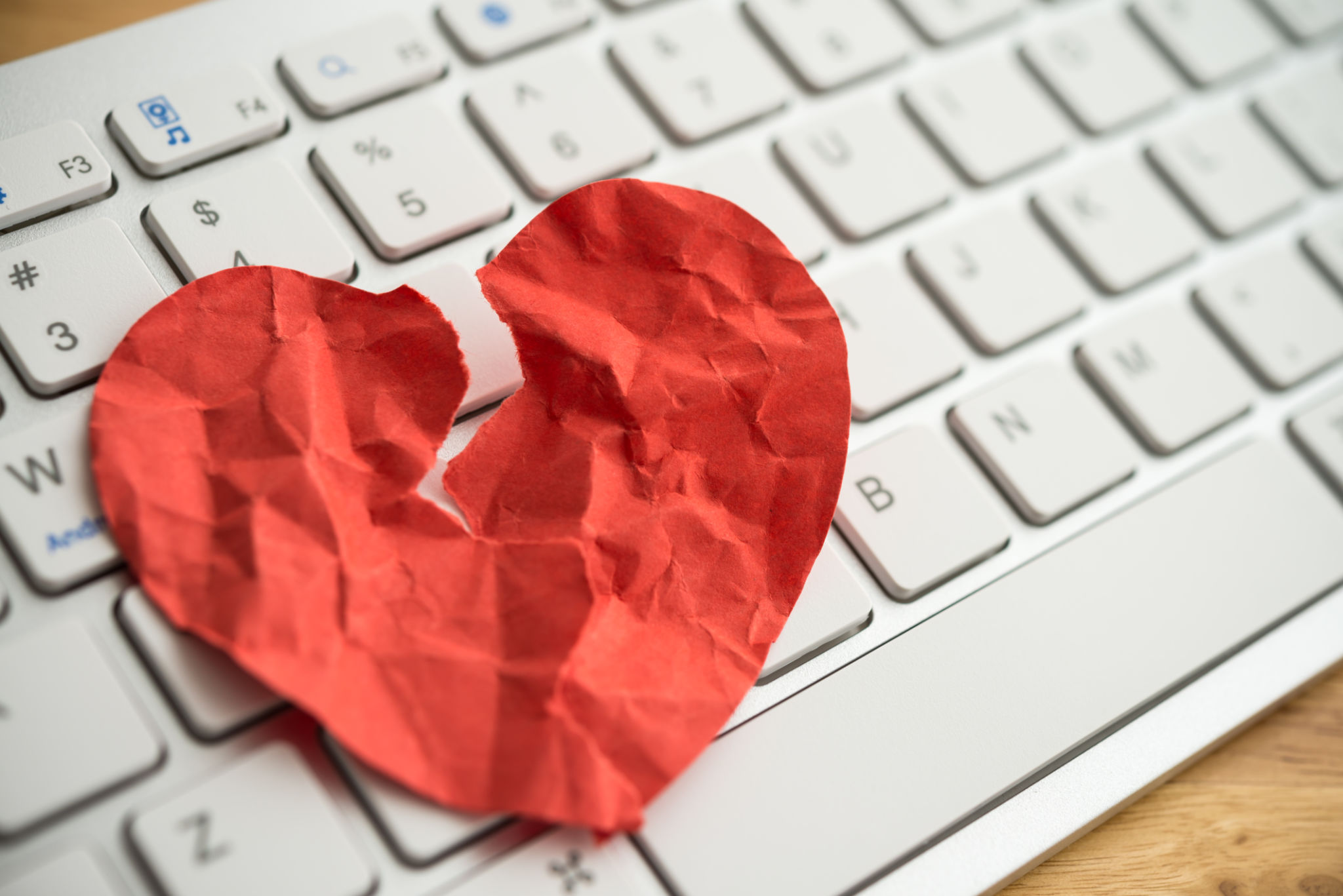 Red broken heart paper on white keyboard computer background. Red broken heart paper on white keyboard computer background.