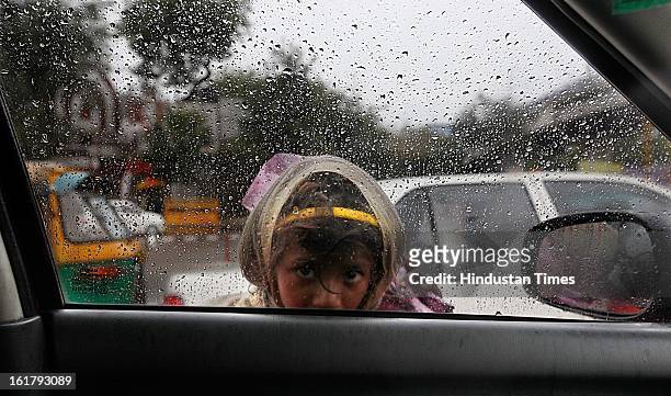 An infant looking through car glass window with misty eyes as it rains with overcast sky near India Gate , on February 16, 2013 in New Delhi, India....