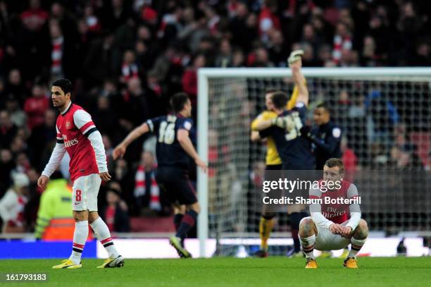 Dejected Arsenal players Mikel Arteta and Jack Wilshere look on as Blackburn players celebrate their team's 1-0 victory during the FA Cup with...