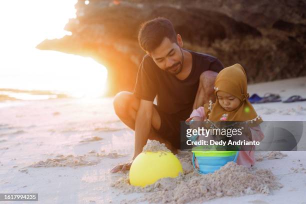 retrato da filha do pai muçulmano brincando na praia ao pôr do sol - muslim woman beach - fotografias e filmes do acervo