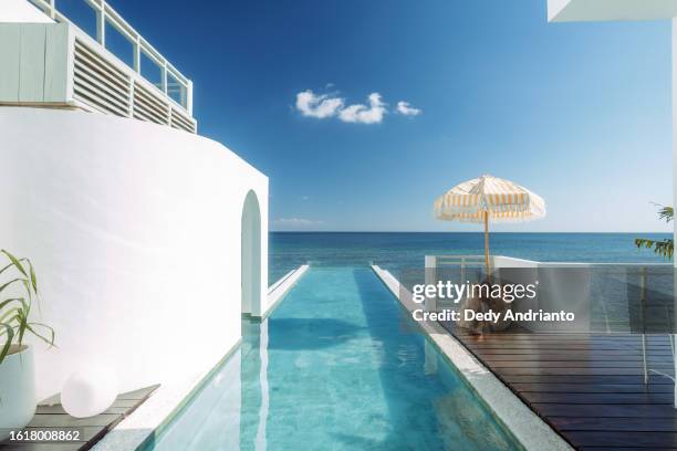 beautiful indonesian relaxing under yellow stripped umbrella at the infinity pool side - upper class stock pictures, royalty-free photos & images