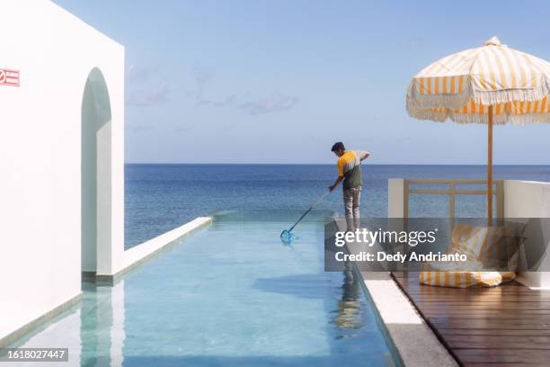 Técnico limpiando alberca infinity de resort de lujo frente al mar
