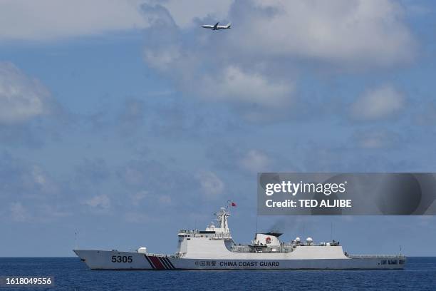 This photo taken on August 22, 2023 shows a US Navy's P-8 Poseidon patrol and reconnaissance plane circling past a Chinese coast guard ship during...