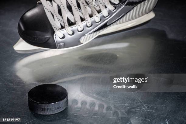 ice skate and hockey puck - hockey player black background stock pictures, royalty-free photos & images