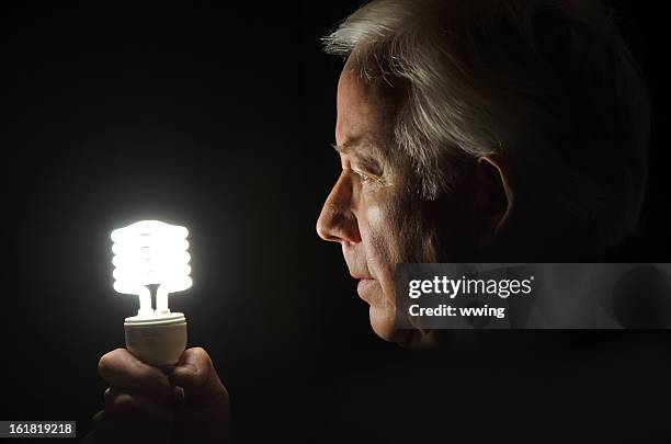 energy saving light bulb ... handheld - fluorescent light stock pictures, royalty-free photos & images