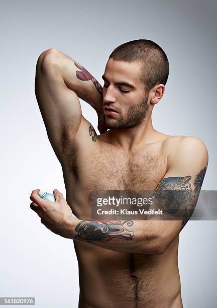 handsome man with tatoo's spraying deodorant - deodorant photos et images de collection