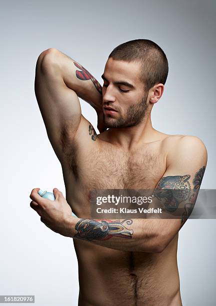 handsome man with tatoo's spraying deodorant - deodorant stock pictures, royalty-free photos & images