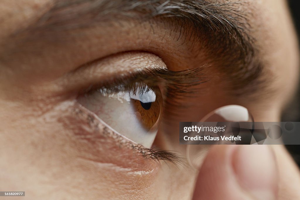 Close-up of man putting in contact lens