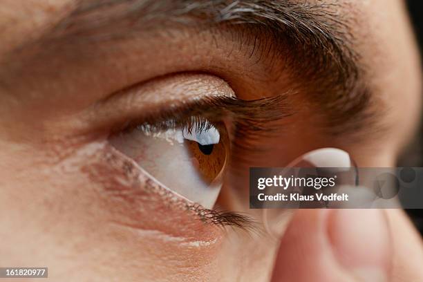 close-up of man putting in contact lens - contact lens stock pictures, royalty-free photos & images