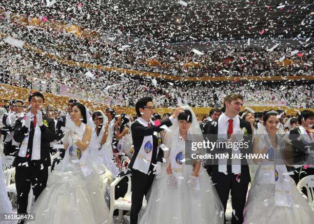 Newly-married couples applaud at the end of the mass wedding organised by the Unification Church and held in its headquarters in Gapyeong, east of...